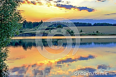 Evening landscape screensaver on the lake with the reflection in the water of the evening sky filled with sun. Stock Photo