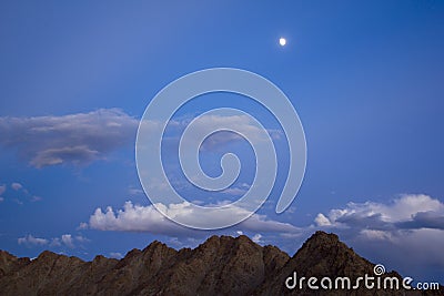 A evening, night dark blue sky with clouds with stars and the moon over the desert mountains Stock Photo