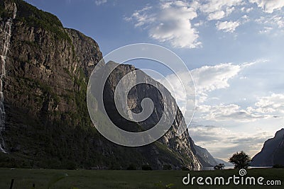 Evening shot of beautiful fjord valley, surrounded by mountains, cloudy blue skies Stock Photo