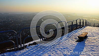 Evening view on cityscape from viewpoint hill with steel rail and old bench during snowy season. Location Nitra city, Slovakia Stock Photo
