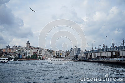 Evening view of Galata tower district, buildings, bridge with people fishing and Bosporus sea water with boats, seagulls and cloud Editorial Stock Photo