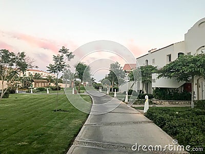 Evening view of the stone path and Arabian Muslim whiteness of building, cottages amidst the tropical green of palm trees and pla Stock Photo