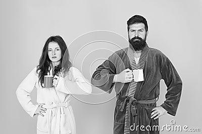 Every morning begins with coffee. Couple in bathrobes with mugs. Breakfast concept. Man with beard and sleepy woman Stock Photo