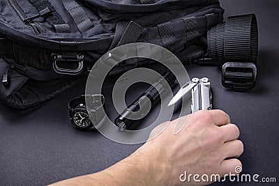 Everyday carry EDC items for men in black color - backpack, tactical belt, flashlight, watch and silver multi tool. Stock Photo