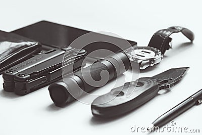Everyday carry EDC items for men in black color on white background - flashlight, watch, multi tool multitool, phone, pen. Stock Photo