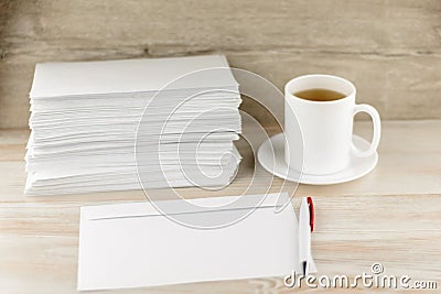 Everyday life of an office worker - monotonous stack of envelopes, an envelope and pen lie ahead on the desktop, with a fresh Cup Stock Photo