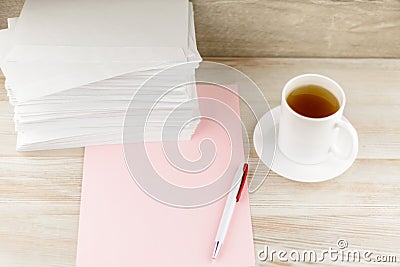 Everyday life of an office worker - monotonous stack of envelopes, a sheet of pink paper and pen lie ahead on the desktop, with a Stock Photo