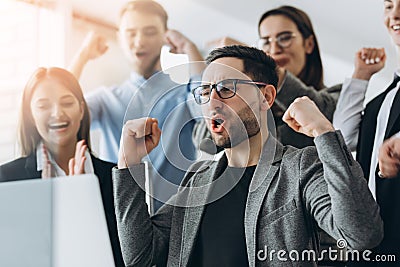 Everyday winners. Group of happy business people in smart casual wear looking at the laptop and gesturing. Achieving success Stock Photo