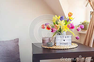 Everything for a calm stay at home. Lightbox with Stay home message, bouquet of fresh spring flowers and candles on the coffee Stock Photo