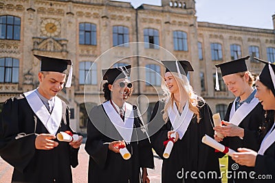 Cheerful graduating students glad having their diplomas. Stock Photo