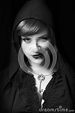 Evil young bad woman. Witch hooded head. Smirk expression. Black background Stock Photo