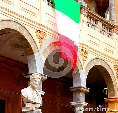 Italian flag hanging from a building with the bust of Dante in the foreground Stock Photo