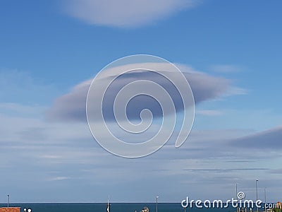 Lens shaped cloud with the sea in the distance Stock Photo