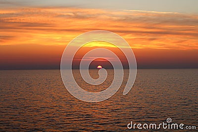 Sunrise over the sea with the sun rising over the horizon Stock Photo