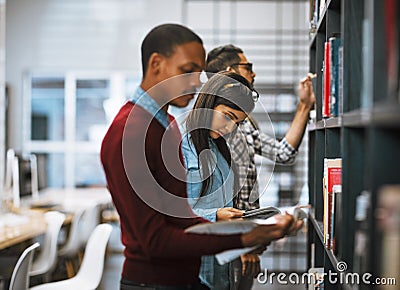 In exam time the library is your best friend. a group young students standing in a library picking out books to read. Stock Photo