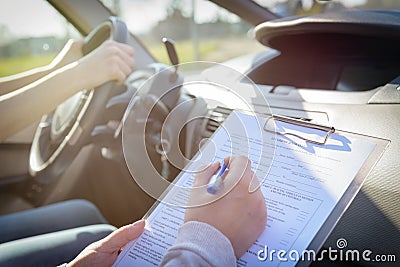 Examiner filling in driver`s license road test form Stock Photo