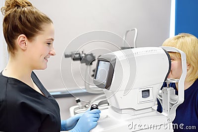 Examining of fundus of mature woman by female ophthalmologist using retinal scanner. Patient during visit to optometrist for Stock Photo