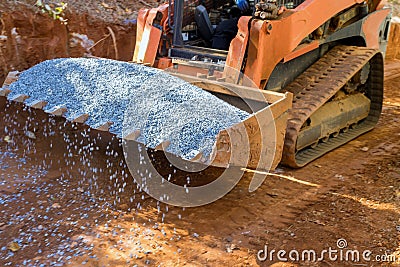 An excavator bucket rakes in crushed stone the excavator is picking up a full bucket Stock Photo