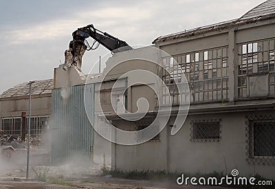 An excavator claw demolish an old factory building Stock Photo