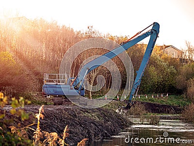 Excavator cleaning and deepening small river. Stock Photo