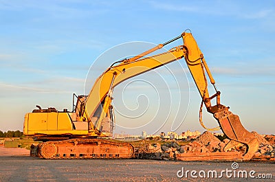 Excavator on a construction site cuts and crumbles old concrete and asphalt. Stock Photo