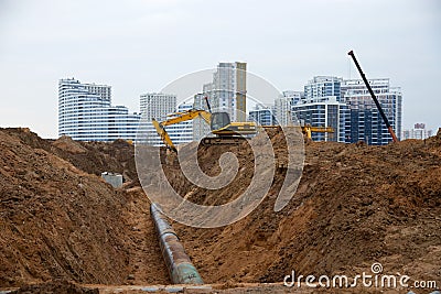 Excavator at construction site during laying sewer and main reticulation systems. Civil infrastructure pipe, water lines, sanitary Stock Photo