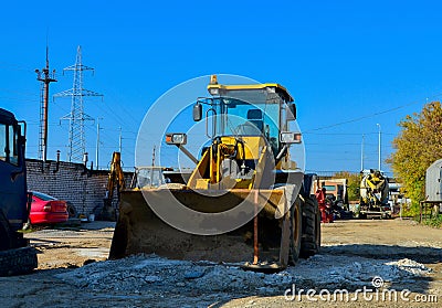 Excavator on the construction site is preparing to load the soil into the dump truck. Wheel loader with iron bucket Stock Photo