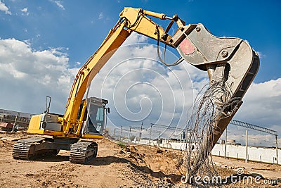 Excavator crasher machine crushing pole wit jaws on construction site Stock Photo