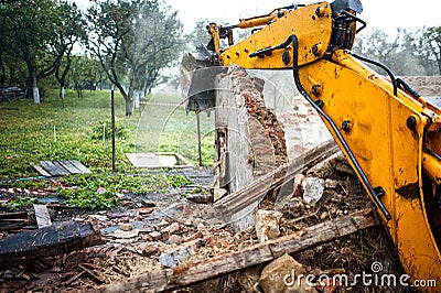 Excavator demolishing a concrete wall Stock Photo