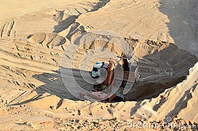 Excavator developing the sand on the opencast and loading it to the heavy dump truck. Processing of loose material in mining Editorial Stock Photo