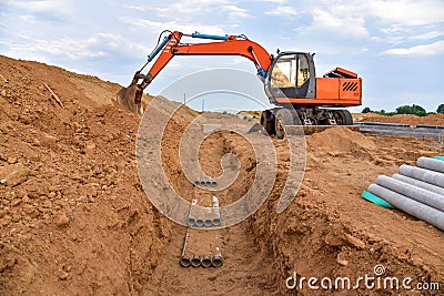 Excavator dig the trenches at a construction site. Trench for laying external sewer pipes. Sewage drainage system for a multi- Stock Photo