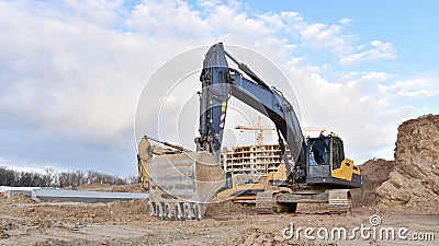 Excavator during excavation at construction site. Backhoe on foundation work in sand pit. Groundworks, site levelling, Stock Photo