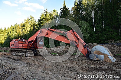 Excavator during groundwork at forest area for construction new road. Orange backhoe on road work, land clearing, grading, Stock Photo
