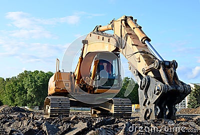Excavator with hydraulic shears breaks asphalt on a construction site. Hydraulic shear crusher pulverizer for excavator. Stock Photo