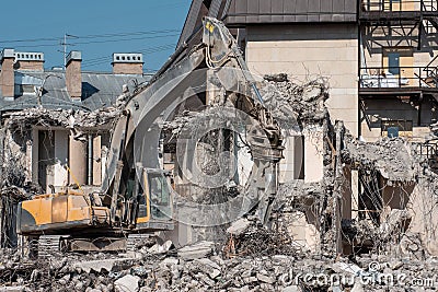 Excavator with hydraulic shears for dismantling the ruins of the house, demolition Stock Photo