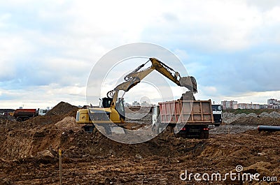 Excavator load the sand to the heavy dump truck on construction site. Excavators and dozers digs the ground for the foundation Stock Photo