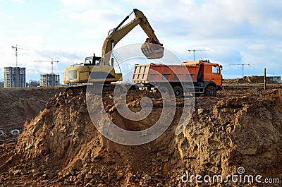 Excavator load the sand to the heavy dump truck on construction site. Excavators and dozers digs the ground for the foundation Stock Photo