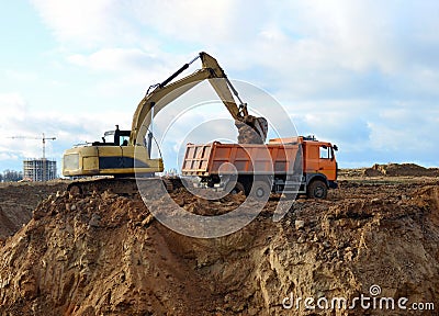 Excavator load the sand to the heavy dump truck on construction site. Excavators and dozers digs the ground for the foundation Stock Photo