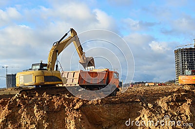 Excavator load the sand to the heavy dump truck on construction site. Excavators and dozers digs the ground for the foundation Stock Photo