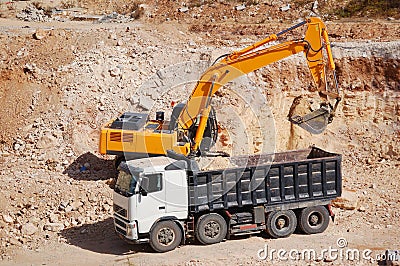 Excavator loading dumper truck with sand Stock Photo