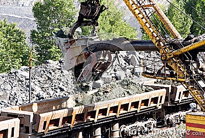 Excavator loading iron ore into goods wagon. Iron ore opencast mine Stock Photo