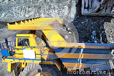 Excavator loading iron ore into heavy dump trucks Stock Photo