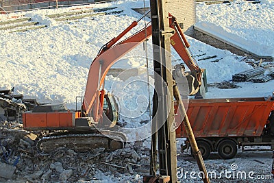 Excavator loads soil into a truck at a construction site in winter in Russia Stock Photo