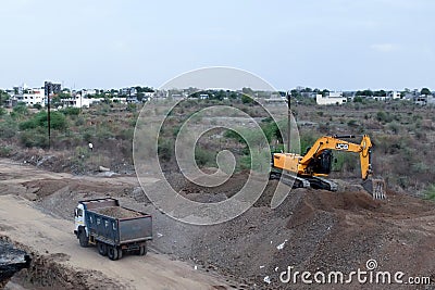 The Excavator machine is lifting the rocky soil and filling it in the dumper truck on construction Editorial Stock Photo