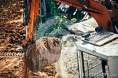 Excavator moving earth on construction site. Close-up of bucket full of earth Stock Photo