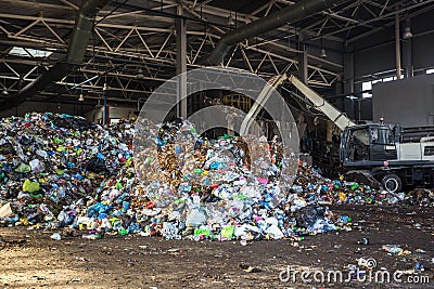 Excavator stacks trash in big pile at sorting modern waste recycling processing plant. Separate and sorting garbage collection. Stock Photo