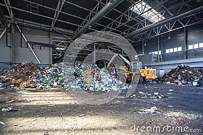 Excavator stacks trash in big pile at sorting modern waste recycling processing plant. Separate and sorting garbage collection. Stock Photo