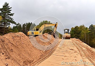 Excavator and Vibro Roller Soil Compactor at road construction and bridge projects in forest area. Heavy machinery for road work. Stock Photo