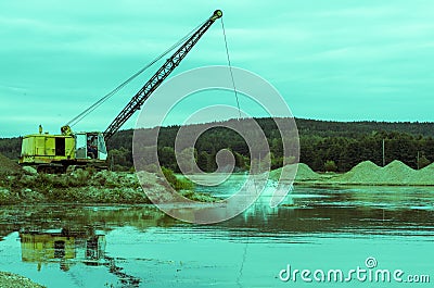 Excavator working in the river gravel quarry against the background of the forest. Extraction of natural resources Stock Photo