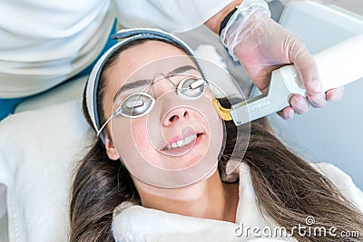 Excel V laser skin treatment on female patient, in a beauty clinic. Laser made by Cutera. Logo shows on hand-piece, with circular Editorial Stock Photo